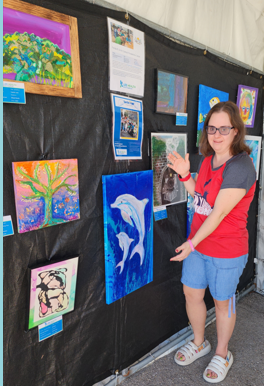 Young woman standing next to a wall filled with artwork.