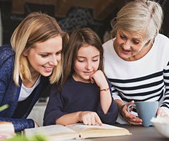 Grandmother, mother and daughter reading