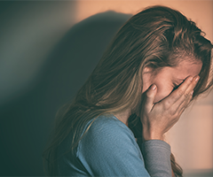 Woman holding head in hands