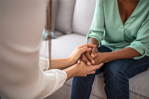 A provider comforting a patient by holding their hands