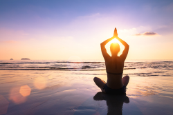 Individual doing yoga on the beach at sunrise