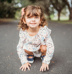 Little girl squatting outside