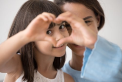 Little girl and mom making a heart shape with hands 