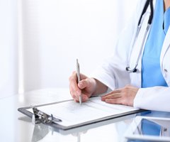 Physician writing on clipboard