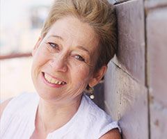 Woman smiling, leaning on wall