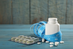 Pills next to a pill jar and a measuring tape