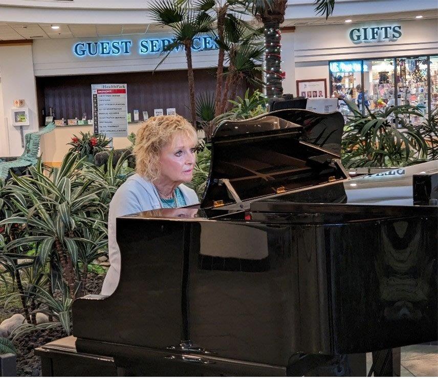 Woman playing piano, woman playing cello and woman playing flute in hospital lobby