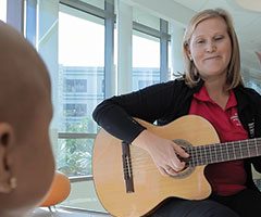 Woman playing guitar for pediatric patient
